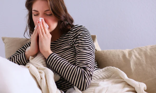 Portretul unei femei bolnave care își suflă nasul în timp ce stă pe canapea — Fotografie, imagine de stoc