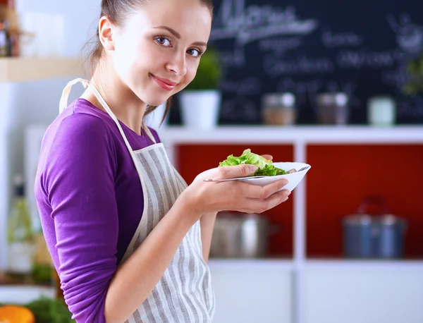 Νεαρή γυναίκα τρώει φρέσκια σαλάτα στη σύγχρονη κουζίνα — Φωτογραφία Αρχείου
