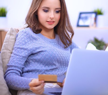 Bilgisayarı ve kredi kartıyla gülümseyen güzel bir kadın.