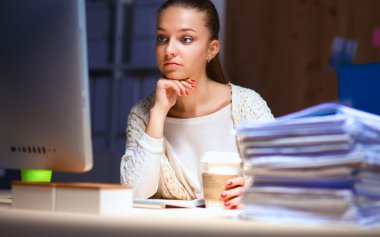 Ofiste çalışan genç kadın masada oturan ve telefonda konuşmak