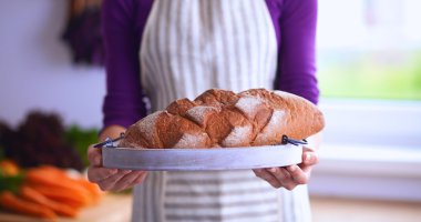 Genç bir kadın mutfağında lezzetli taze ekmek tutuyor.