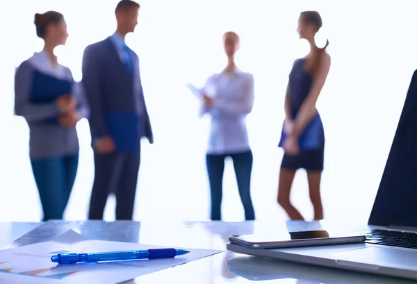 Laptop auf dem Schreibtisch, Geschäftsleute im Hintergrund — Stockfoto