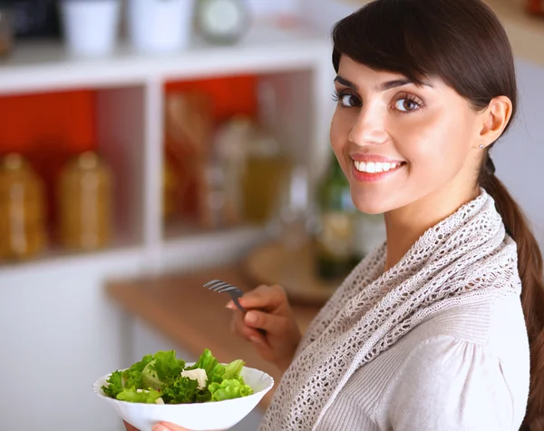 Mujer joven comiendo ensalada fresca en la cocina moderna — Foto de Stock