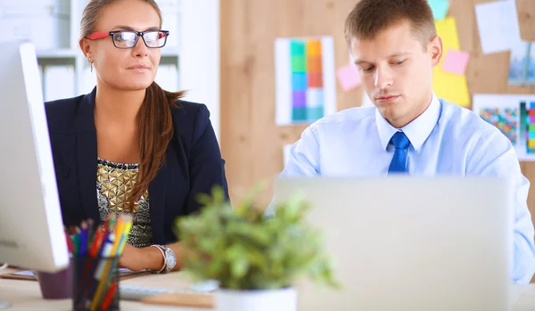 Fashion designers working in studio sitting on the desk — Stock Photo, Image