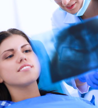 Kadın dişçi hastalarının dişlerinde çalışıyor.