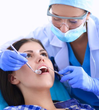 Kadın dişçi hastalarının dişlerinde çalışıyor.