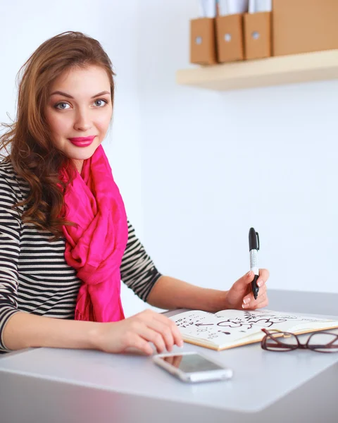Молодая женщина пишет дневник на белом столе — стоковое фото