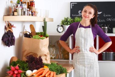 Onun mutfak masa alışveriş torbaları ile yakın duran genç kadın