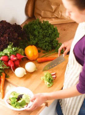 Mutfakta sebze doğrayan genç bir kadın.