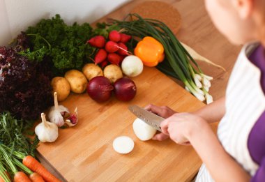 Mutfakta sebze doğrayan genç bir kadın.