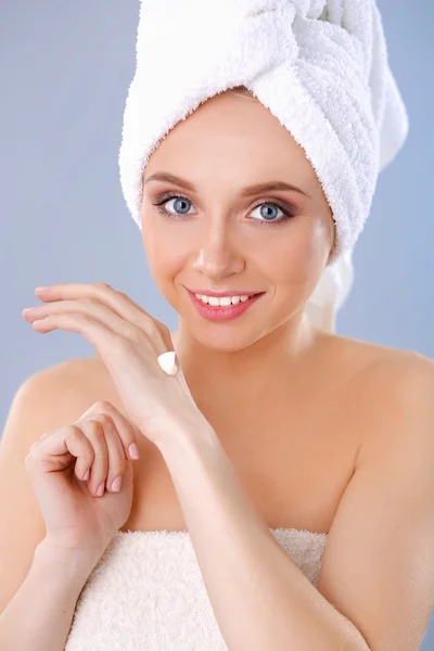 Mujer joven poniendo crema en su mano Aislado sobre fondo gris — Foto de Stock