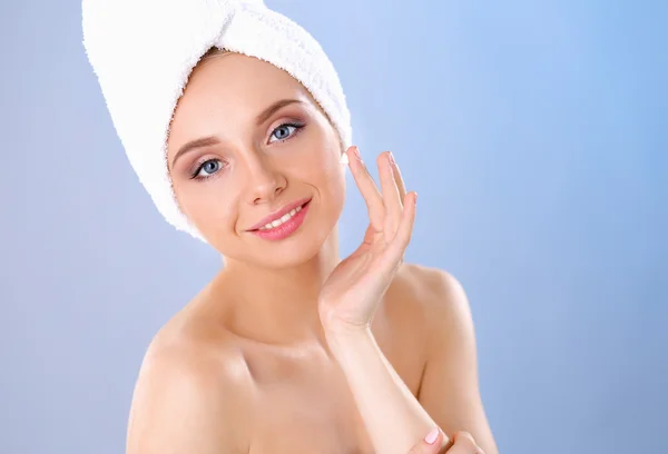 Hermosa joven aplicando una crema en su cara aislada sobre fondo gris —  Fotos de Stock