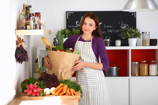 야채 가방을 들고 부엌에 서 있는 젊은 여자 — 스톡 사진