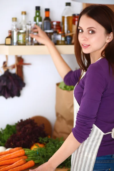 Jovem mulher de pé em sua cozinha perto da mesa com sacos de compras — Fotografia de Stock