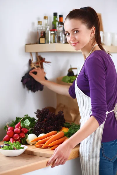 Mujer joven cortando verduras en la cocina — Foto de Stock