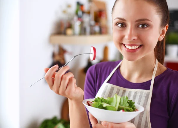 Genç kadın modern mutfakta taze salata yiyor. — Stok fotoğraf