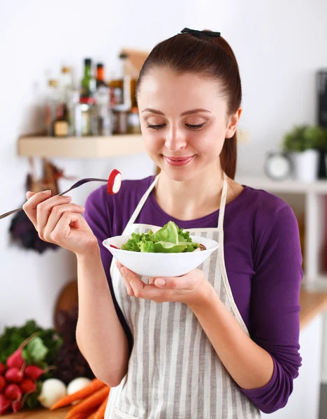 Mujer joven comiendo ensalada fresca en la cocina moderna —  Fotos de Stock