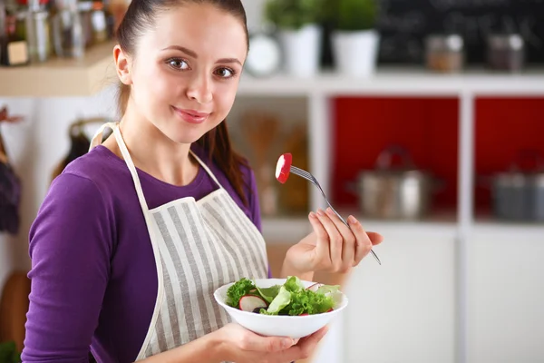 Mujer joven comiendo ensalada fresca en la cocina moderna — Foto de Stock