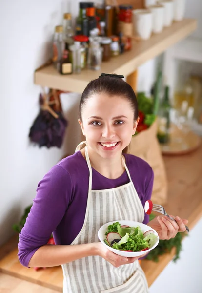 Mujer joven comiendo ensalada fresca en la cocina moderna —  Fotos de Stock