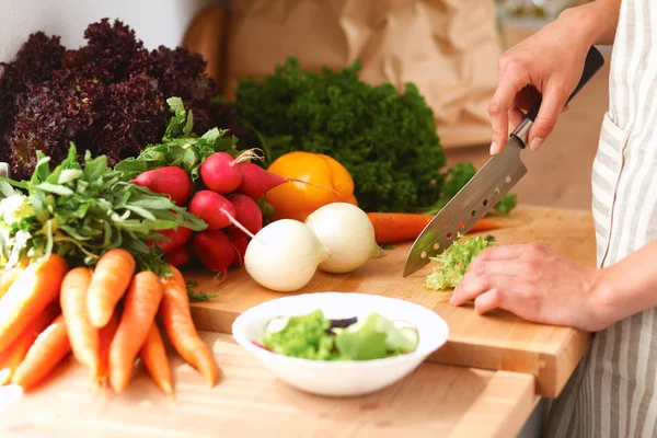 Jovem mulher cortando legumes na cozinha — Fotografia de Stock
