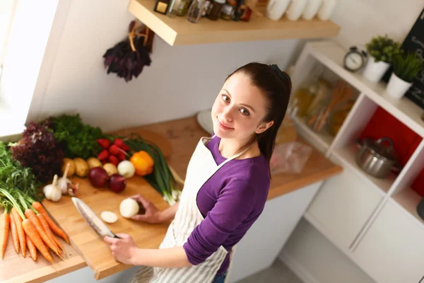 Jovem mulher cortando legumes na cozinha — Fotografia de Stock