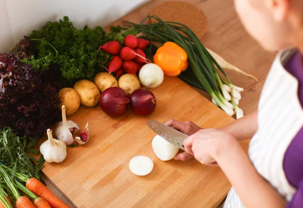 Mutfakta sebze doğrayan genç bir kadın.