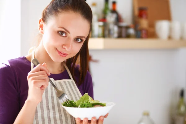 Young woman eating fresh salad in modern kitchen — Stock Photo, Image