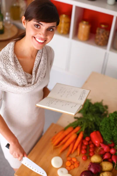 Mujer joven leyendo libro de cocina en la cocina, buscando receta —  Fotos de Stock