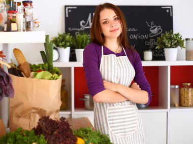 Onun mutfak masa alışveriş torbaları ile yakın duran genç kadın