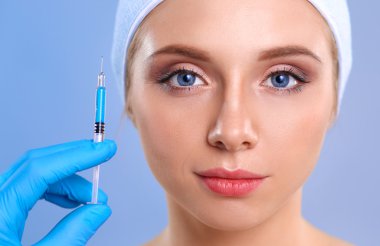 Güzel kadın yüz kozmetik enjeksiyon. Gri arka plan üzerinde izole