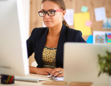 Moda tasarımcıları stüdyoda çalışıyor. Masanın üzerinde oturuyorlar.