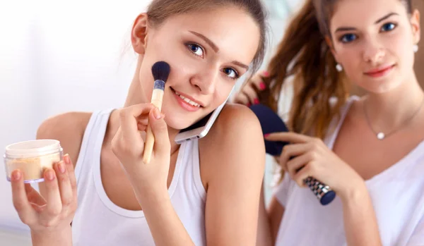 Schöne Mädchen, die in den Spiegel schauen und Kosmetik mit einem großen Pinsel anwenden — Stockfoto