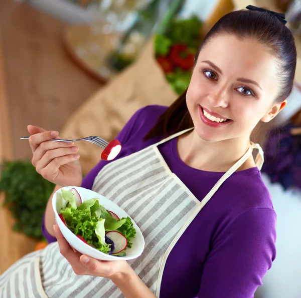 Jovem mulher comendo salada fresca na cozinha moderna — Fotografia de Stock