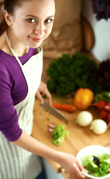 Jonge vrouw die groenten snijdt in de keuken — Stockfoto