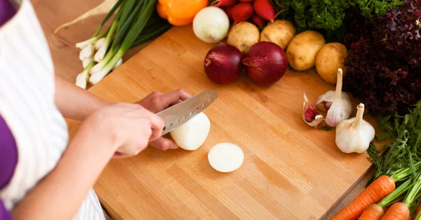 Mutfakta sebze doğrayan genç bir kadın.