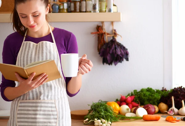 Junge Frau liest Kochbuch in der Küche und sucht Rezept — Stockfoto