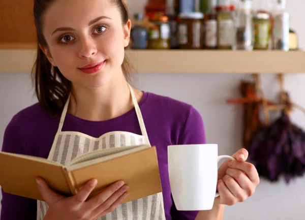 Mujer joven leyendo libro de cocina en la cocina, buscando receta —  Fotos de Stock