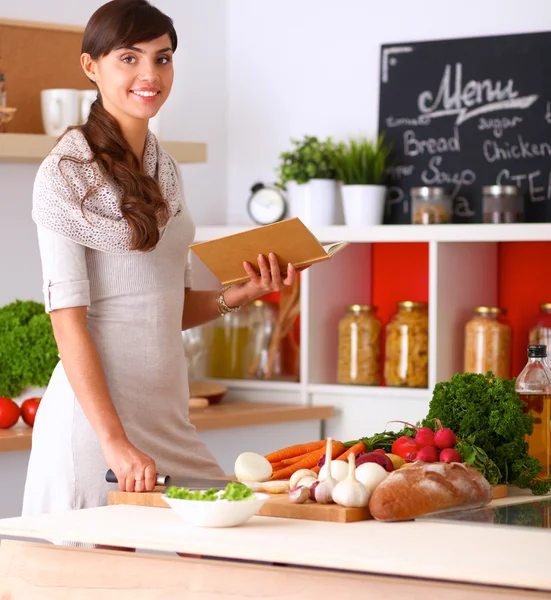 Jonge vrouw in haar keuken in de buurt van Bureau met shopping tassen — Stockfoto