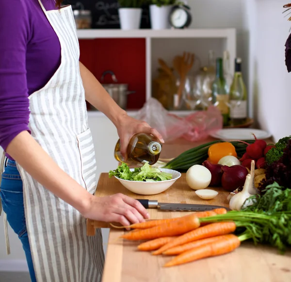 Jonge vrouw die groenten snijdt in de keuken — Stockfoto