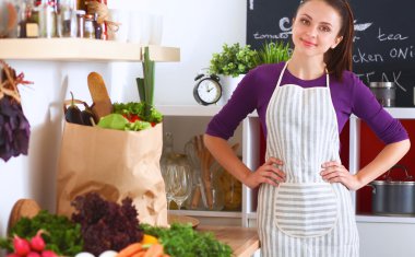 Onun mutfak masa alışveriş torbaları ile yakın duran genç kadın