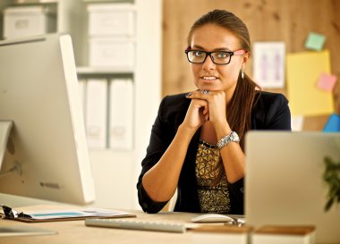 Moda tasarımcıları stüdyoda çalışıyor. Masanın üzerinde oturuyorlar.