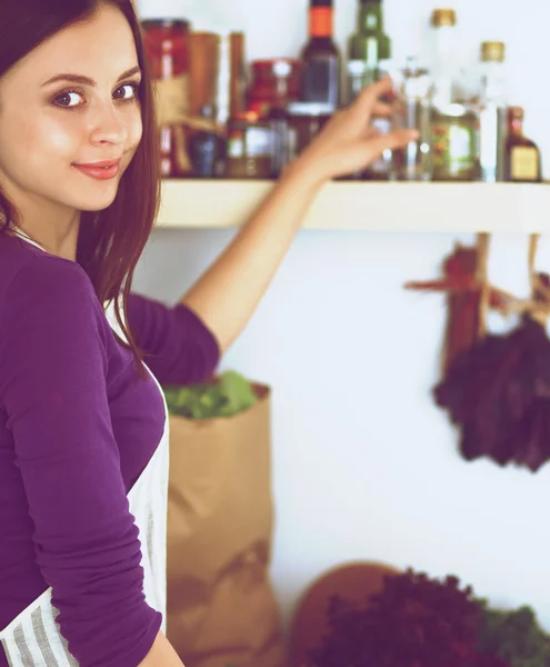 Mujer joven de pie en su cocina cerca del escritorio —  Fotos de Stock