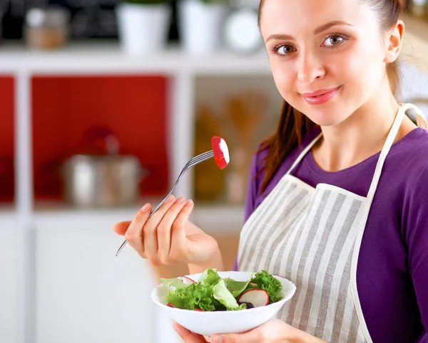 Mujer joven comiendo ensalada fresca en la cocina moderna — Foto de Stock