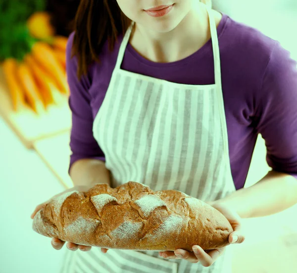 Mujer joven sosteniendo sabroso pan fresco en su cocina —  Fotos de Stock
