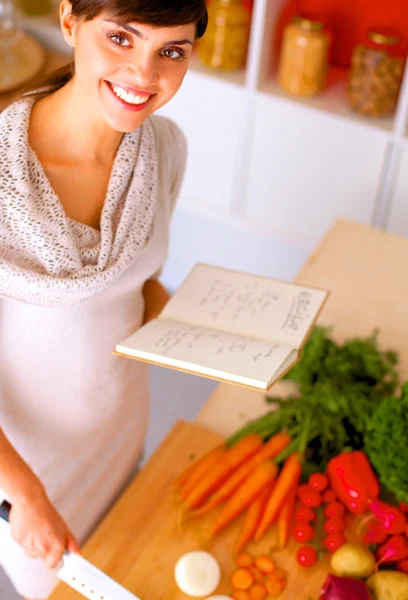 Mujer joven leyendo libro de cocina en la cocina, buscando receta —  Fotos de Stock