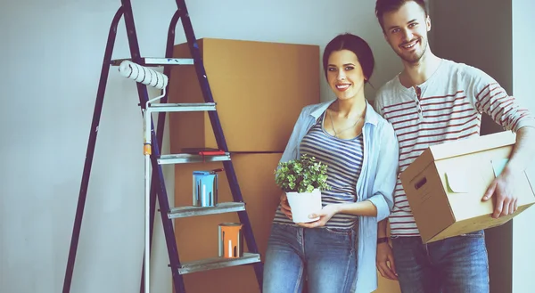 Feliz jovem casal desembalagem ou embalagem caixas e se mudar para uma nova casa — Fotografia de Stock