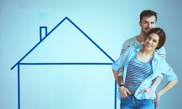 Couple standing in front of painted home on wall — Stock Photo, Image