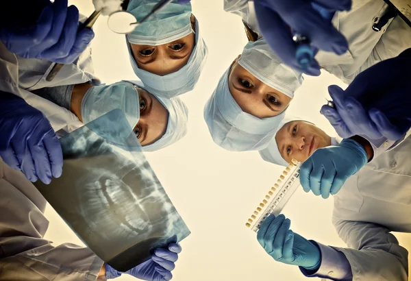 Equipe de cirurgiões, homem e mulher vestindo uniformes protetores, bonés e máscaras — Fotografia de Stock