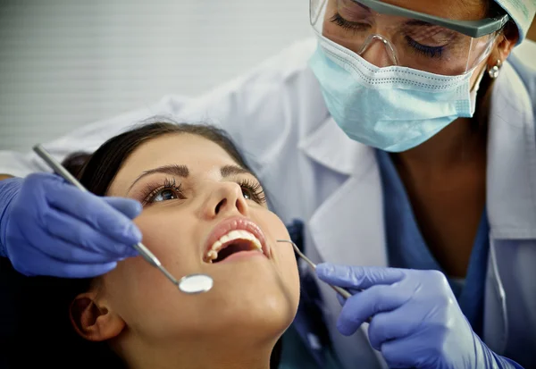 Женщина-дантист, работающая над зубами пациента — стоковое фото