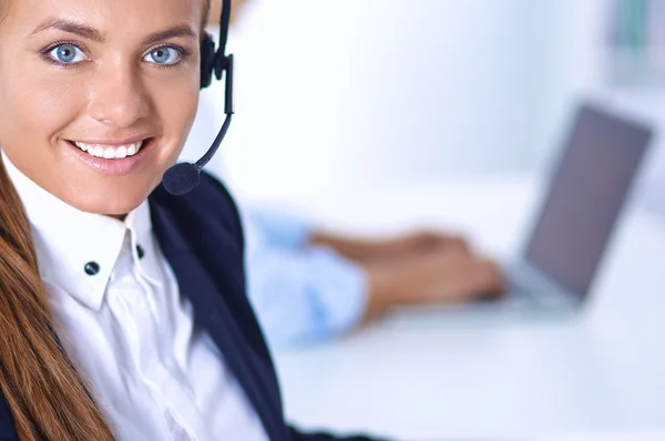 Glückliche Frau trägt Headset und sitzt auf dem Schreibtisch — Stockfoto